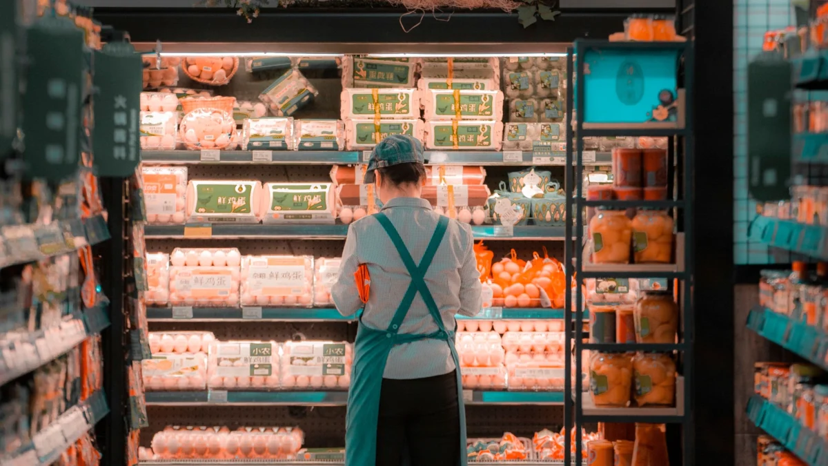 Supermarket employee organizing products on stocked shelves
